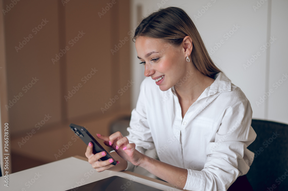 Cute young business woman in a white blouse with the phone in hand Cute young business woman in a white blouse with the phone in hand