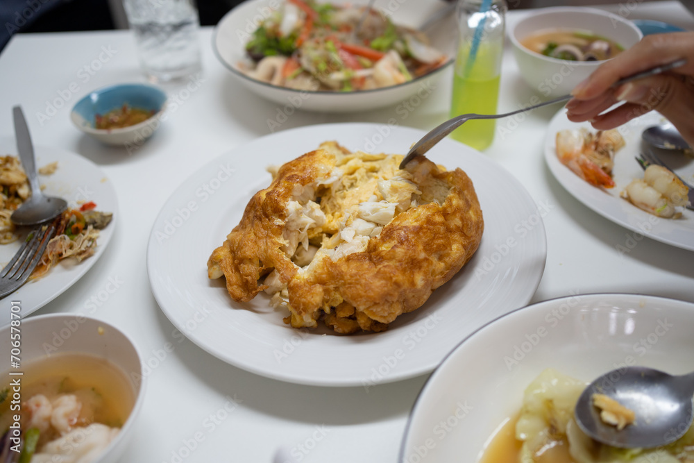 Crab omelette close up with hand with forks.