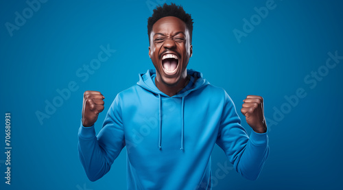 Homme noir, heureux, criant, le poing serré, arrière-plan bleu, image avec espace pour texte