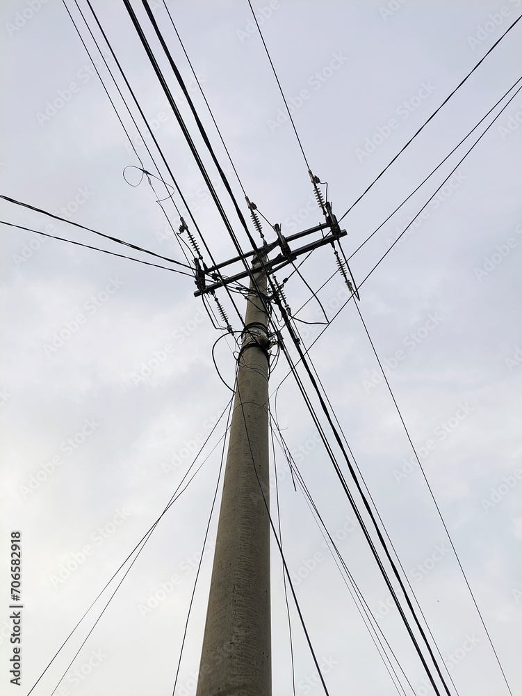 Electric pole with tangled cables, photographed from below in the afternoon Electric pole with tangled cables, photographed from below in the afternoon