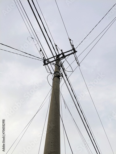 Electric pole with tangled cables, photographed from below in the afternoon