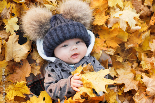 Cute baby lying in autumn leaves.  Smiling baby lying at autumn park with colorful of maple leaves.