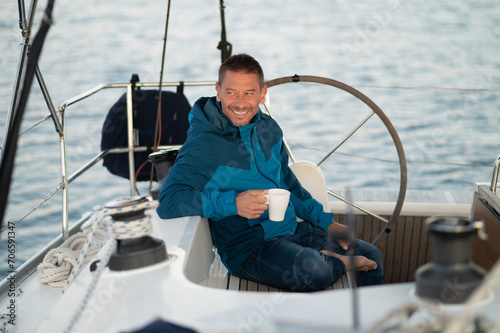 Man in blue jacket on the yacht having coffee and looking contented © zinkevych