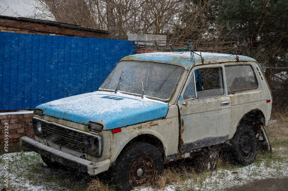 Obraz premium Old rusty, broken, abandoned car near the blue fence