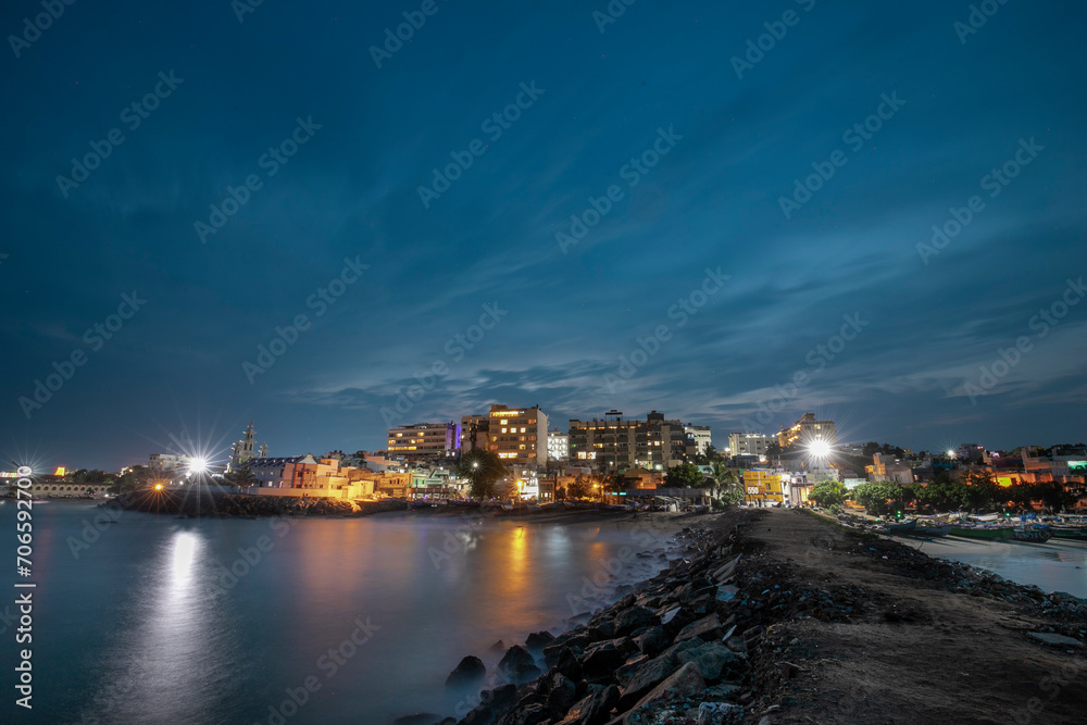cloudy sky blue hour of the port city Kanyakumari  tamilnadu India with street light and reflections on sea waters
