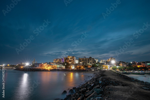 cloudy sky blue hour of the port city Kanyakumari tamilnadu India with street light and reflections on sea waters