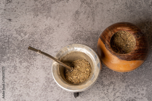 Yerba Mate tea next to a gourd filled with yerba mate, on a light gray background.