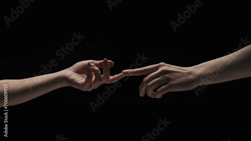Portrait of female model isolated on black background in studio. Two women naked hands stretching to each other touch fingers.