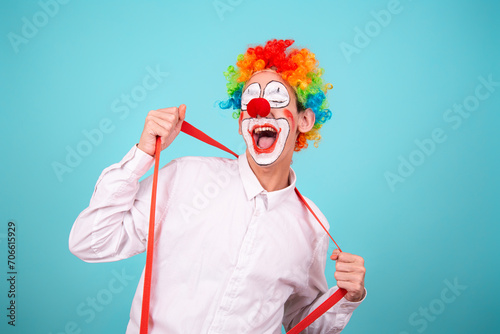 A joyful clown. A cute man in a suit and makeup for a holiday for children. A fool. Blue background. Copy the space. photo