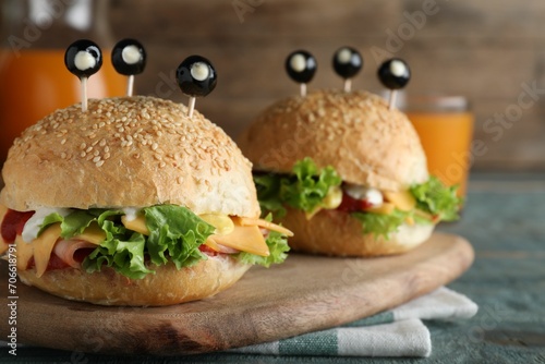 Cute monster burgers served on blue wooden table. Halloween party food photo