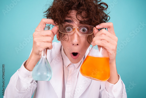 A funny doctor conducts chemical experiments with liquids. A man with test tubes. The study of the interactions of substances. Blue background.