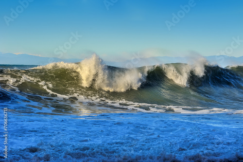 powerful great waves on the sea crests with foam, mountains in the distance o...