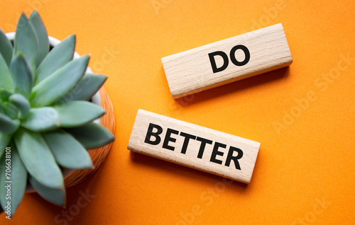 Do better symbol. Wooden blocks with words Do better. Beautiful orange background with succulent plant. Business and Do better concept. Copy space.
