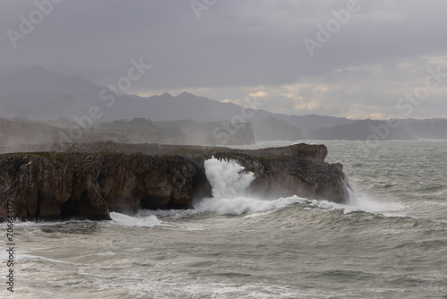 Bufones de Pria in Asturias coast on a cloudy day with rough seas and wave spray © Barosanu