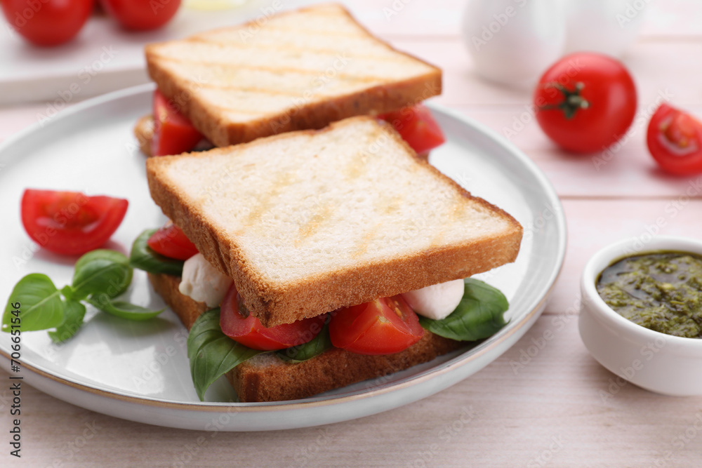 Delicious Caprese sandwiches with mozzarella, tomatoes, basil and pesto sauce on white wooden table, closeup Delicious Caprese sandwiches with mozzarella, tomatoes, basil and pesto sauce on white wooden table, closeup