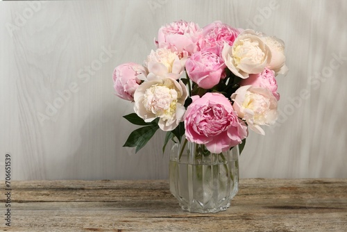 Beautiful peonies in vase on wooden table, space for text © New Africa