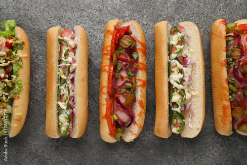 Delicious hot dogs with different toppings on grey table, flat lay