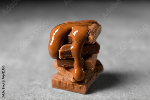 Pieces of milk chocolate with tasty paste on gray table, closeup