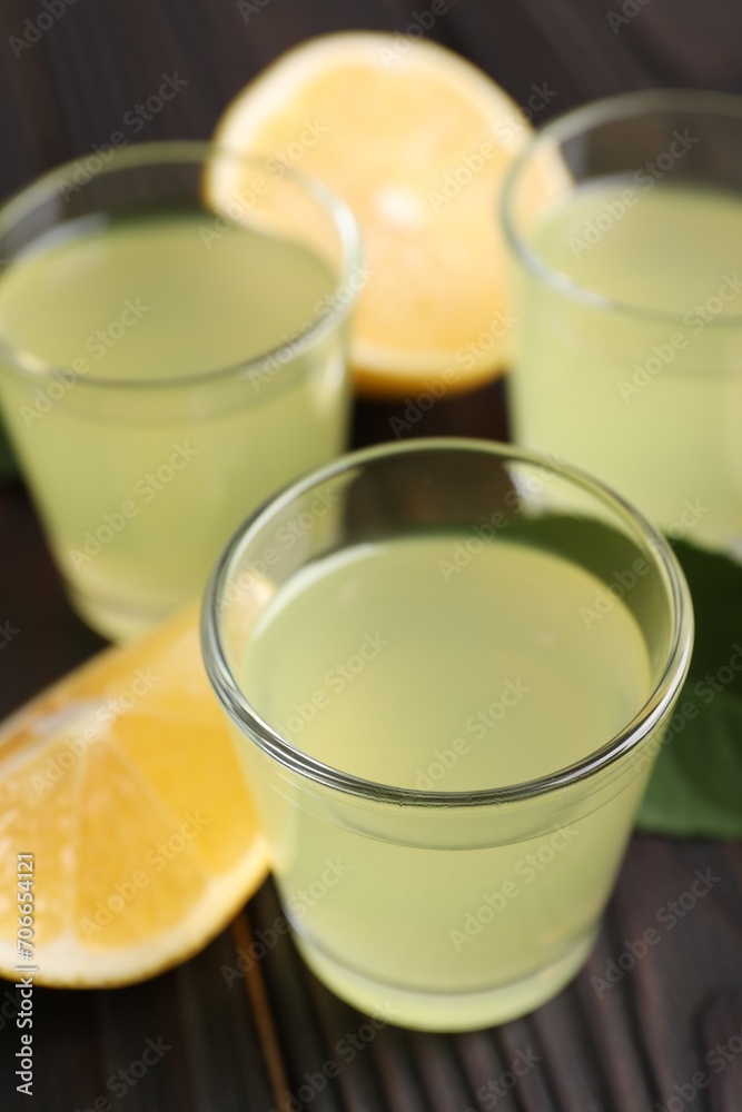 Tasty limoncello liqueur and lemon on dark wooden table, closeup Tasty limoncello liqueur and lemon on dark wooden table, closeup