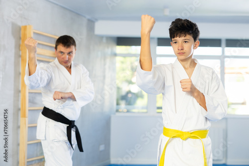 Karate trainer teaching block and punches to a teenager in the gym