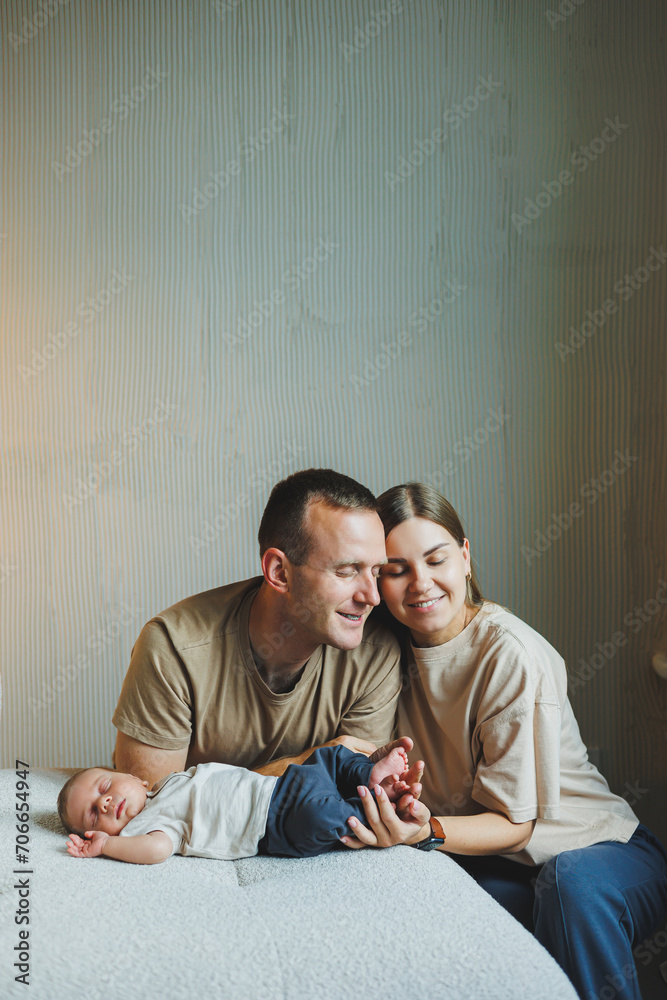 A young family with a newborn baby. Happy mother and father kissing their child. Parents and a smiling child in their arms A young family with a newborn baby. Happy mother and father kissing their child. Parents and a smiling child in their arms