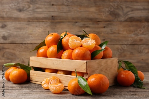 Delicious tangerines with leaves on wooden table