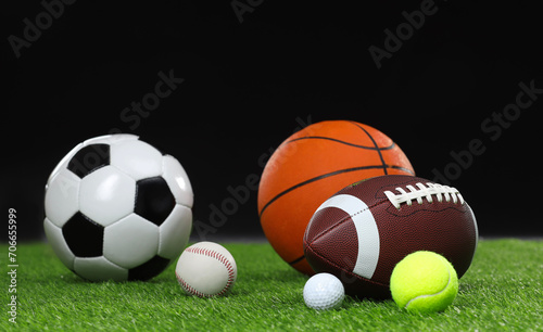 Many different sports balls on green grass against black background © New Africa