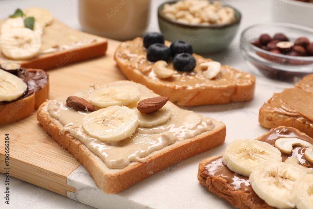 Toasts with different nut butters, fruits and nuts on table, closeup
