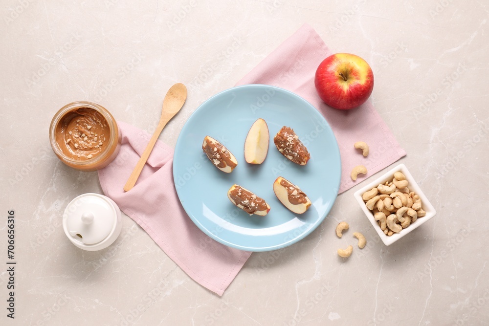 Slices of fresh apple with nut butter and cashews on light marble table, flat lay