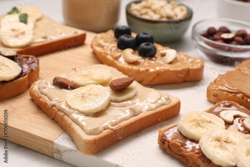 Fototapeta Naklejka Na Ścianę i Meble -  Toasts with different nut butters, fruits and nuts on table, closeup