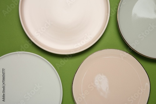 Beautiful ceramic plates on green background, top view