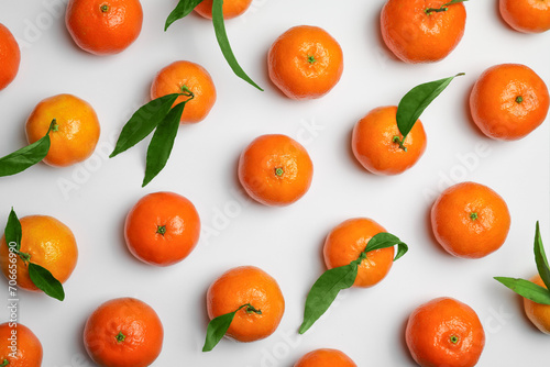 Delicious tangerines and green leaves on white background, flat lay