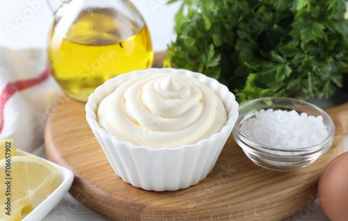 Fresh mayonnaise sauce in bowl and ingredients on table, closeup