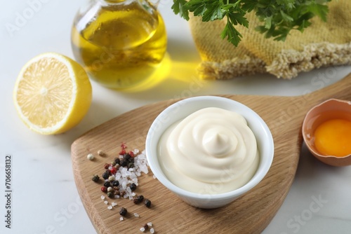 Tasty mayonnaise sauce in bowl, ingredients and spices on white table, above view