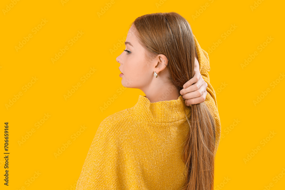 Obraz premium Fashionable young woman in knitted sweater on yellow background