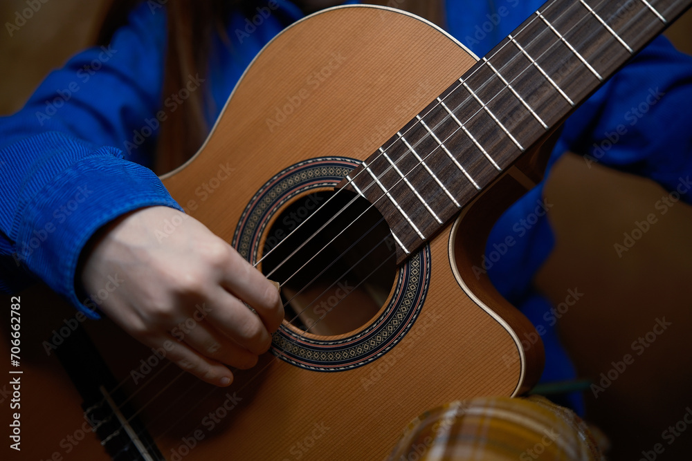 Fototapeta premium Close up professional classical guitar. Teenager hands in blue shirt playing. Music lesson, art education.