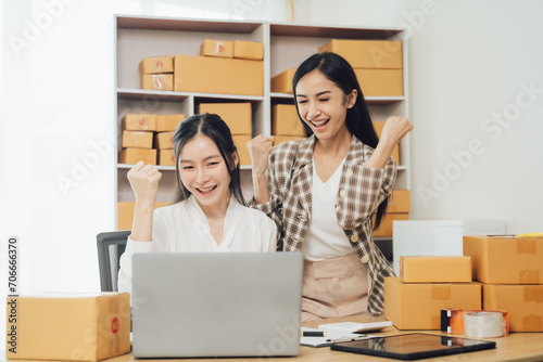 Two businesswomen celebrating online sales success in office. Concept of e-commerce and achievement © Nittaya