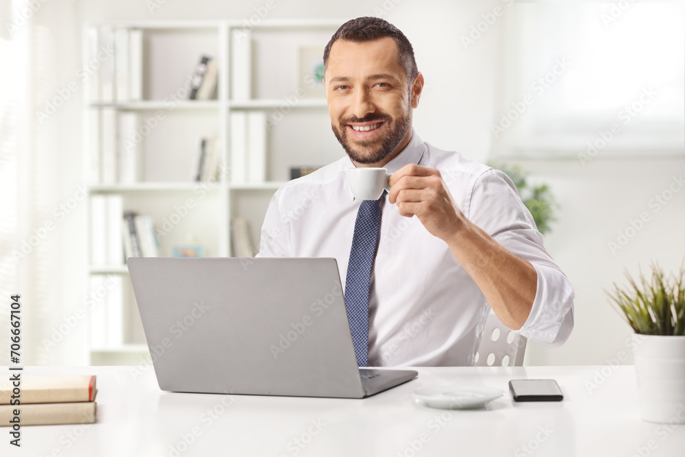 Man drinking coffee behind a laptop computer Man drinking coffee behind a laptop computer