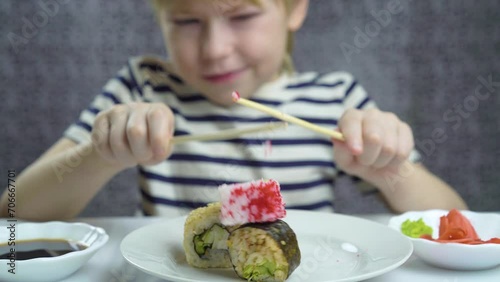 child awkwardly tries to eat sushi and rolls