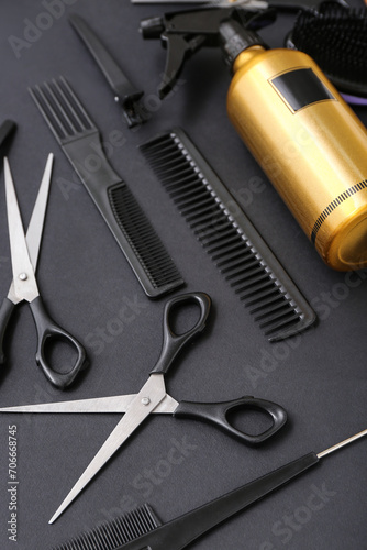 Composition with hairdressing accessories and spray bottle on black background, closeup