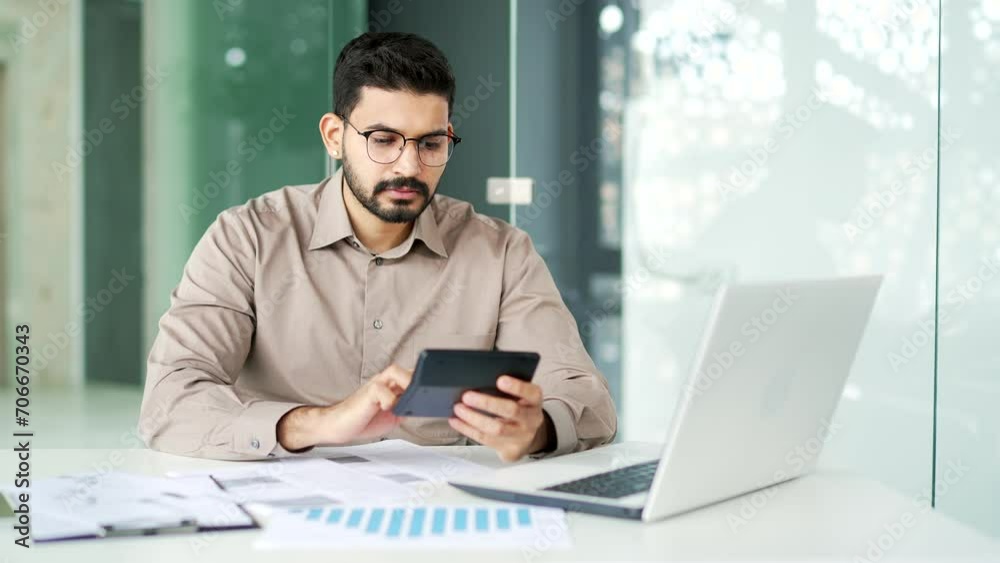 Busy financier is doing paperwork using a digital tablet while sitting at the workplace. Confident bearded businessman working fills out documents, writing, making a tax return in business office Busy financier is doing paperwork using a digital tablet while sitting at the workplace. Confident bearded businessman working fills out documents, writing, making a tax return in business office