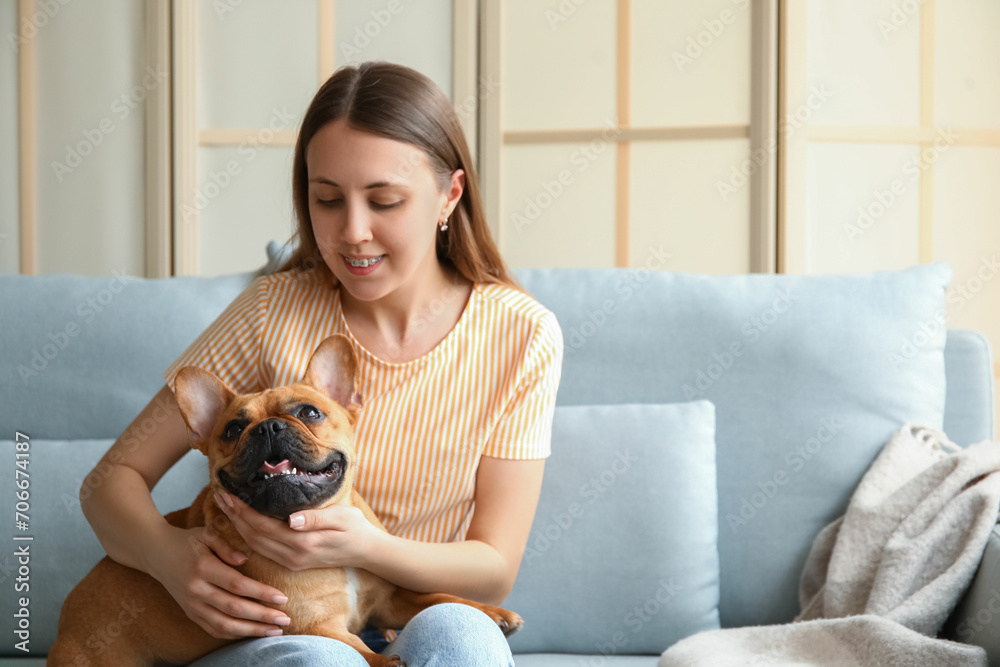 Young woman with cute French bulldog sitting on sofa at home Young woman with cute French bulldog sitting on sofa at home
