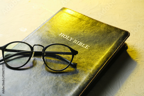 Holy Bible with eyeglasses on grey background, closeup