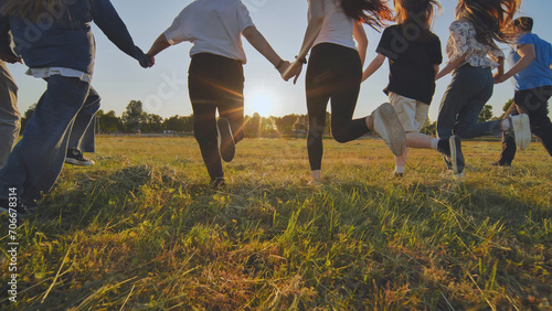 Young boys running at sunset across the field holding hands.