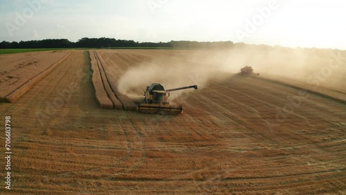 Combine harvester with unload pile cuts dry wheat in farm field aerial view. Reaping machine harvests rich cereal crop working on plantation photo