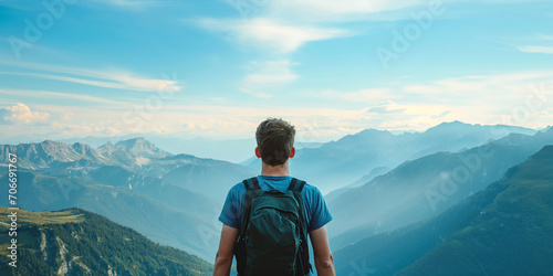 Happy young tall man with backpacks from behind standing and enjoying life in the mountains, man enjoying the view from top of mountain, close up back view. photo