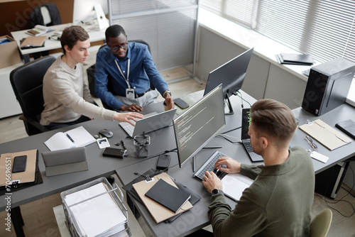 High angle shot of busy IT professionals sitting at office desks while developing cybersecurity protocols during workday in modern IT company photo