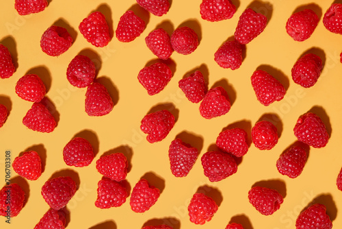 Many fresh raspberries on yellow background