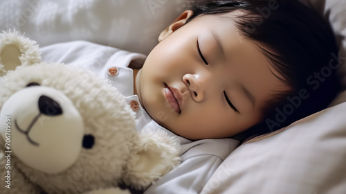 portrait of a charming sleeping baby with a cute teddy bear on a comfortable bed.