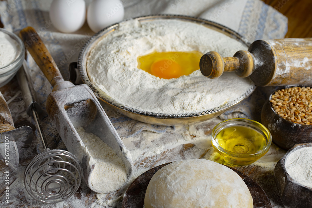 The process of kneading dough in the kitchen. Eggs, flour and other ingredients on the kitchen table in a composition. The process of kneading dough in the kitchen. Eggs, flour and other ingredients on the kitchen table in a composition.